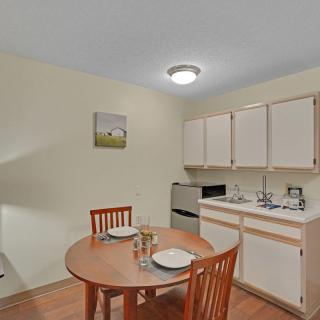 A small kitchen with a dining table and chairs, featuring cabinets, a sink, and appliances.