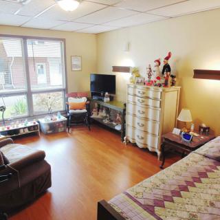 A cozy bedroom with comfortable furnishings and natural light from a large window.