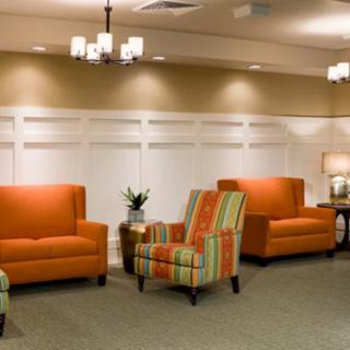 A modern waiting room with orange and striped seating, featuring warm lighting and contemporary decor.