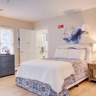 A cozy bedroom with a well-made bed, decorated with elegant linens and a bedside lamp on a wooden nightstand.