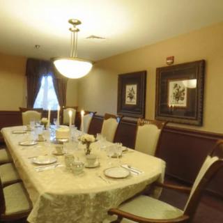 A formal dining room setup with a long table, elegant chairs, and soft lighting.
