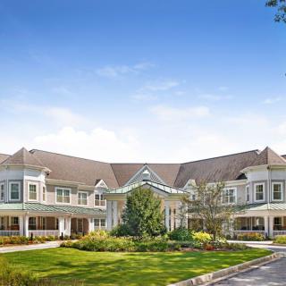 A large, elegant residential building with beautifully landscaped gardens in front.
