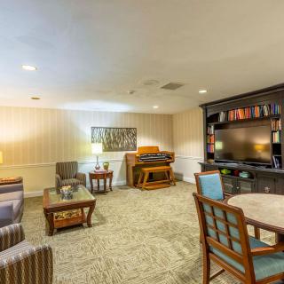 A cozy living room featuring a piano, television, and comfortable seating area.