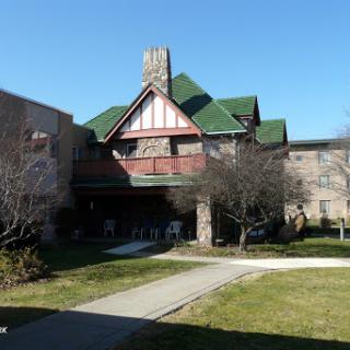 A picturesque view of a building featuring traditional architectural elements, surrounded by green grass and clear blue skies.