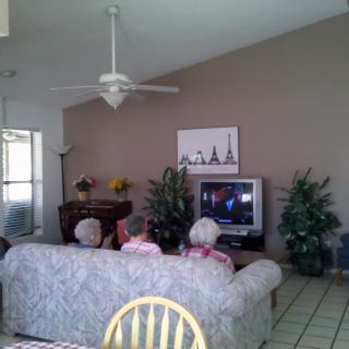 A cozy living room with people watching television.