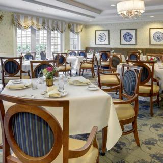 An elegant dining room with neatly arranged tables and chairs, set for guests.