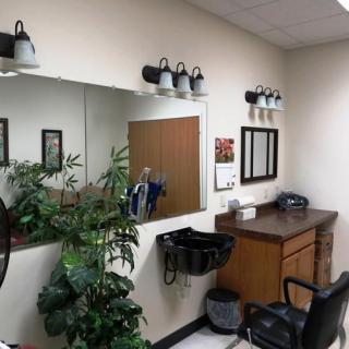 A cozy barber shop with mirrors, styling chair, and decorative plants.