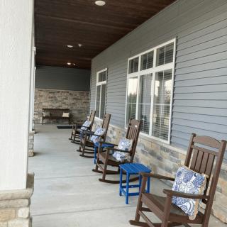 A modern porch with several rocking chairs and decorative cushions.