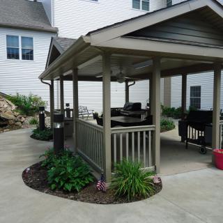 A cozy outdoor gazebo with seating, surrounded by a small garden.