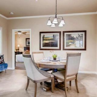 A cozy dining room with a round table, four upholstered chairs, and framed artwork on the wall.
