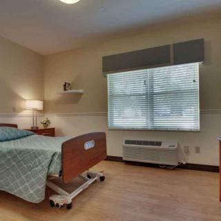 A clean and well-lit hospital room with a single bed and a window.