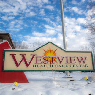 Westview Health Care Center sign displayed against a scenic snowy background.