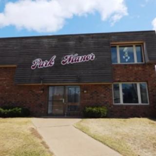 A brick building with a sign reading 'Park Manor' on a clear day.