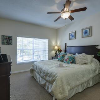 A cozy bedroom with a large bed, ceiling fan, and natural light from the window.