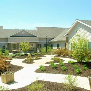 A modern building surrounded by landscaped gardens and winding pathways.