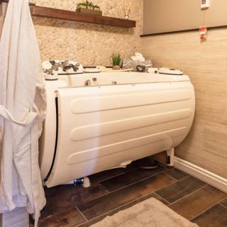 A modern bathroom featuring a jacuzzi-style bathtub with wood accents and tile flooring.
