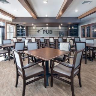 A modern pub interior with neatly arranged tables and chairs, featuring a stylish bar area.