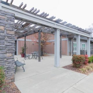 An outdoor patio area featuring a pergola, stone wall, and seating options.