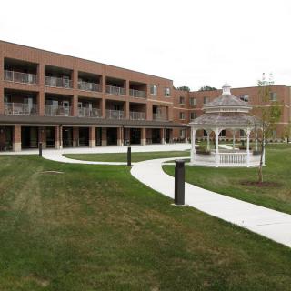 A building with a gazebo and walkway in a landscaped lawn.