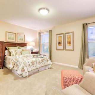 A cozy and elegantly decorated bedroom with a bed, warm lighting, and framed art on the walls.