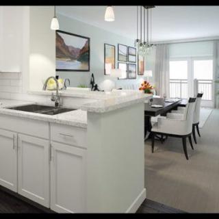 A modern open-concept kitchen and dining area featuring white cabinets and pendant lighting.