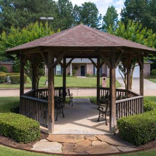 A charming wooden gazebo surrounded by lush greenery, perfect for outdoor relaxation.