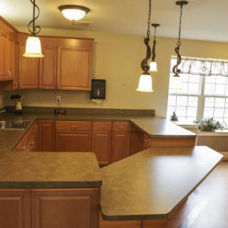 A modern kitchen with wooden cabinets, spacious countertops, and stylish pendant lighting.