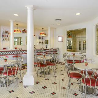 A cozy diner interior featuring red and silver furniture, a classic checkered floor, and warm lighting.