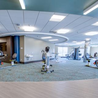 A modern and spacious gym with various exercise equipment arranged in a bright, open workout area.