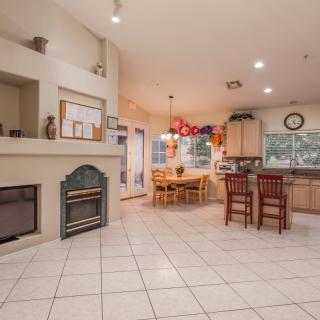 A spacious kitchen and dining area with a fireplace, featuring an open floor plan and tile flooring.