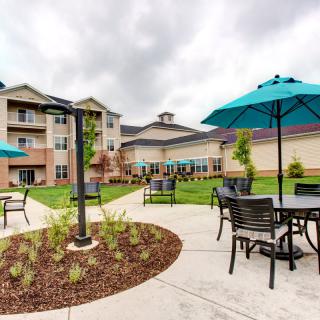 A scenic outdoor patio area with tables and umbrellas in front of a residential building.