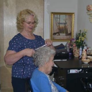 A hairstylist is giving a haircut to an elderly client in a salon.