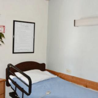A hospital room with a single bed equipped with a pillow and blanket.