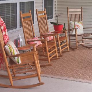 A cozy porch with wooden rocking chairs and colorful cushions.