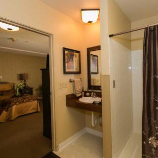 A cozy bathroom connected to a bedroom, featuring a sink, mirror, and shower.