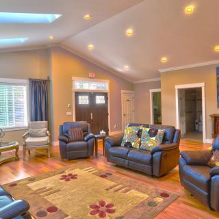 A spacious and cozy living room with blue sofas, wooden flooring, and recessed lighting.