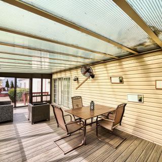 A cozy outdoor patio with a glass roof, featuring a table and chairs for relaxation.