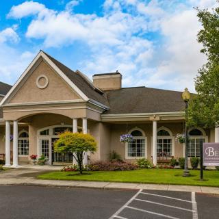A charming building with a gabled roof and columns, set against a partly cloudy sky.