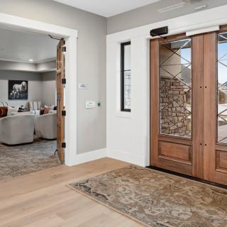 A welcoming entryway with a wooden door and decorative rug leads into a stylish living room.