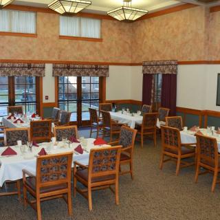 An elegantly set dining room with multiple tables and chairs, ready for guests.