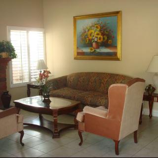 A cozy living room with a sofa, armchair, coffee table, and a painting on the wall.