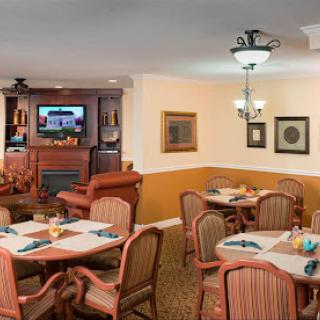 A cozy dining area featuring tables set for guests, comfortable seating, and a television.