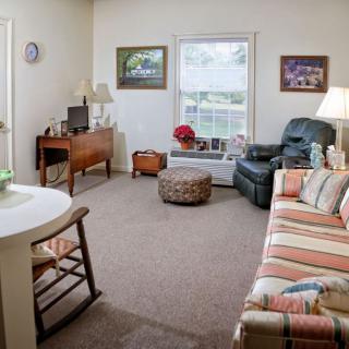 A cozy living room with a striped sofa, armchair, and a small coffee table, featuring a TV and decorative elements.