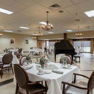 An elegant dining room with neatly set tables and a grand piano.