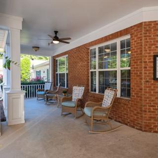 A cozy patio with brick walls, seating arrangements, and a ceiling fan.