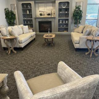 A cozy living room featuring two sofas, a chair, and decorative items on bookshelves.