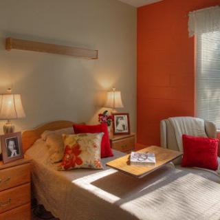 A cozy bedroom with warm lighting and decorative elements, featuring a comfortable bed and personal photos.