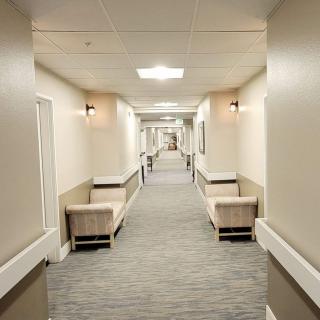 An empty hospital corridor with benches along the walls.
