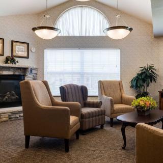A cozy living room featuring comfortable seating, a fireplace, and natural light from a large window.