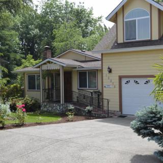 A charming residential house with a driveway and garage, surrounded by trees and a front yard.